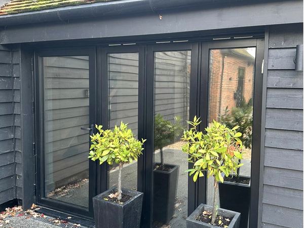 Solar film on black bi-fold doors, reflecting the courtyard