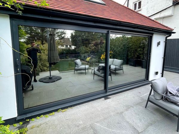 Solar film on large grey sliding doors, reflecting the garden
